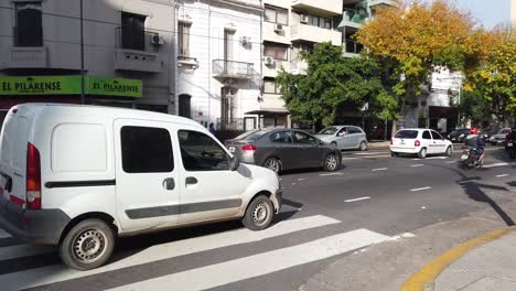 Toma-Panorámica-En-El-Tráfico-De-La-Calle,-Los-Autobuses-Conducen-Muy-Rápido-En-El-Vibrante-Carril-Latino,-Calle-Asfaltada-De-Carabobo-En-El-Barrio-De-Flores,-Vehículos-De-Transporte-De-La-Ciudad-Latina,-Línea-ómnibus-Público-132