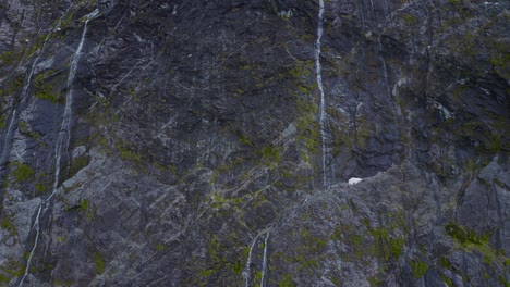 Ruhiger-Aufstieg-über-Felsige-Klippen-Und-Wasserfälle-Offenbaren-Schneebedeckte-Gipfel-In-Fiordland,-Neuseeland,-Südinsel