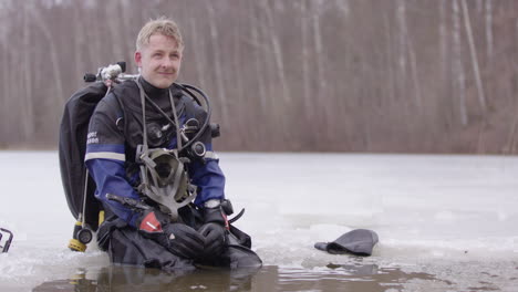 Un-Hombre-Con-Traje-Seco-Y-Equipo-De-Buceo-Técnico-Se-Sienta-En-El-Borde-Del-Agujero-Del-Lago-De-Hielo-Charlando