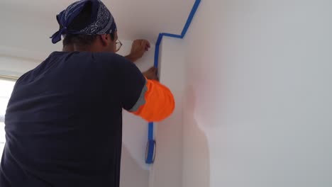 Man-Uses-Blue-Painter's-Tape-For-DIY-Home-Painting
