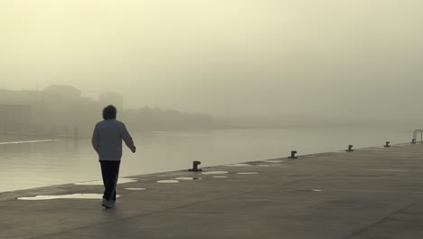 Statische-Ansicht-Eines-Mannes,-Der-Allein-Im-Nebel-Auf-Einem-Pier-Läuft-