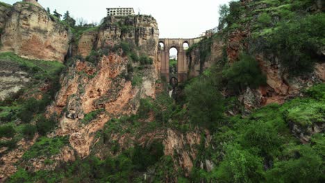 Flyover-hiker-toward-waterfall-and-Puente-Nuevo-bridge-in-Ronda,-Andalusia,-Spain