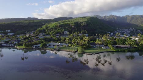 drone-footage-traveling-from-the-still-water-reflecting-palm-trees-on-Mamala-Bay-in-Honolulu-Hawaii-across-the-busy-highway-to-the-lush-mountain-tops-as-the-ecosystems-thrive-together