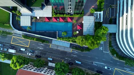 Paisaje-Aéreo-De-Drones-Del-Patio-De-La-Piscina-Del-Complejo-En-La-Concurrida-Calle-Principal-Con-Vehículos-De-Transporte-De-Tráfico-Conduciendo-Farrer-Park-Singapur-Asia-Viajes-Turismo