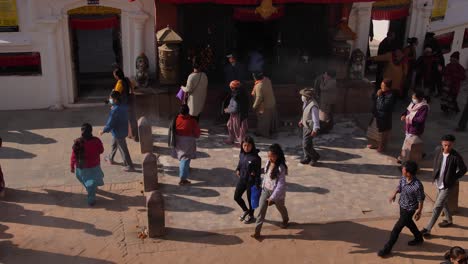 Elevated-view-of-people-walking-past-the-entrance-of-the-Boudhanath-Temple,-Kathmandu,-Nepal