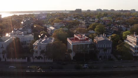 Aerial-close-up-dolly-shot-of-antebellum-mansions-along-White-Point-Garden-in-Charleston,-South-Carolina-at-sunset