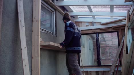 Man-Fitting-Wood-Plank-Onto-Greenhouse-Interior-Wall
