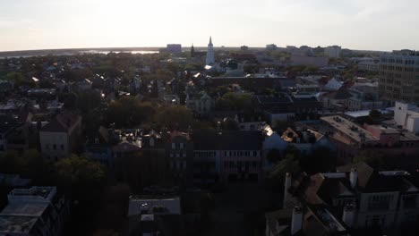 Aerial-wide-reverse-pullback-shot-of-historic-Rainbow-Row-in-Charleston,-South-Carolina-at-sunset