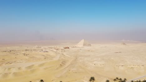 Aerial-of-the-desert-landscape-with-the-Pyramid-of-Djoser,-also-known-as-the-Step-Pyramid-of-Djoser,-an-archaeological-marvel-located-within-the-Saqqara-necropolis-in-Giza,-Egypt