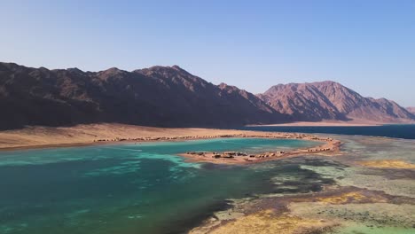 Aerial-of-the-azure-lagoon-in-Dahab,-Egypt,-offers-inspiring-sights-of-the-surrounding-desert-landscape,-promising-visitors-an-unparalleled-and-unforgettable-experience