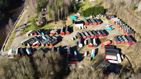 Fishing-Cabins-Clustered-in-Forest-next-to-Sea,-Bohuslan,-Sweden,-Aerial-Circling