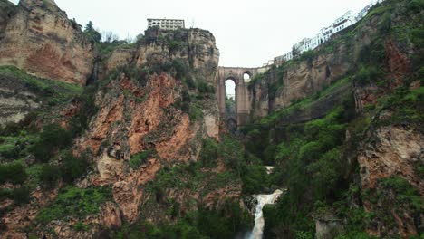 Aerial-4k-drone-pan-up-reveal-toward-waterfall-and-Puente-Nuevo-bridge-in-Ronda,-Andalusia,-Spain