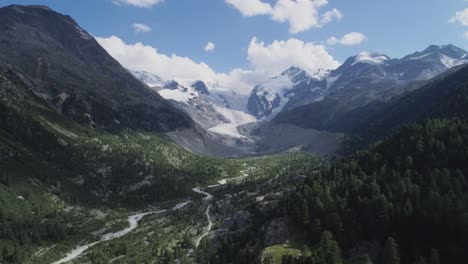 Antena-De-Un-Valle-De-Montaña-Con-Bosques-Y-Ríos-Y-Un-Glaciar-Al-Fondo