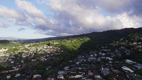 drone-footage-taken-on-the-island-of-Oahu-Hawaii-of-residences-nestled-in-the-lush-greenery-of-the-mountain-ravine-near-Kaawa-as-birds-pass
