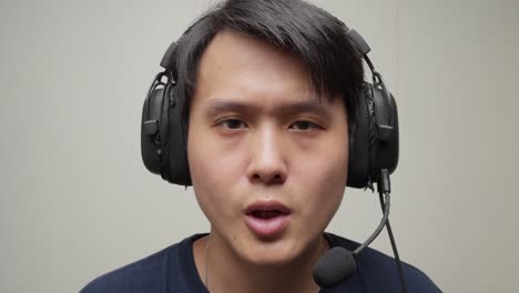 Chinese-man-putting-his-gaming-headset-on-his-head-and-speaks-Hello