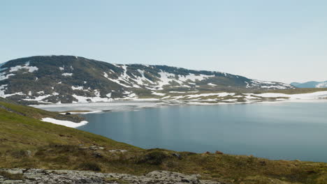 Pequeño-Lago-En-La-Cima-De-Una-Montaña-Cubierta-De-Nieve-En-Verano