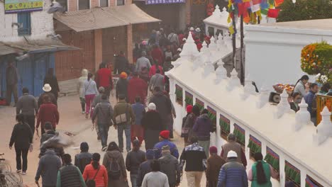Elevated-medium-shot-of-people-walking-around-the-outer-section-of-Boudhanath-Temple,-Kathmandu,-Nepal