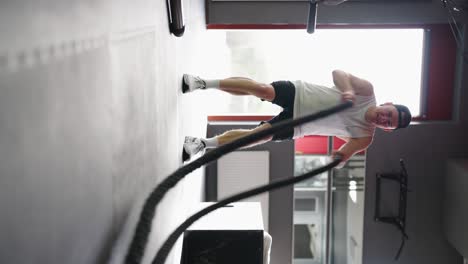 Video-Vertical-De-Un-Atleta-Haciendo-Ejercicios-De-Cuerda-De-Batalla-De-Alta-Intensidad-En-El-Gimnasio.