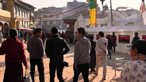 Ground-level-view-of-people-walking-around-the-outer-section-of-Boudhanath-Temple,-Kathmandu,-Nepal