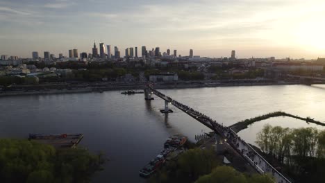 Slow-aerial-pullback-at-sunset-above-river-and-Warsaw-Poland-skyline