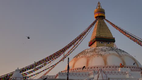 Wide-slow-motion-shot-of-pigeons-flying-around-the-central-Stupa,-Boudhanath-Temple,-Kathmandu,-Nepal