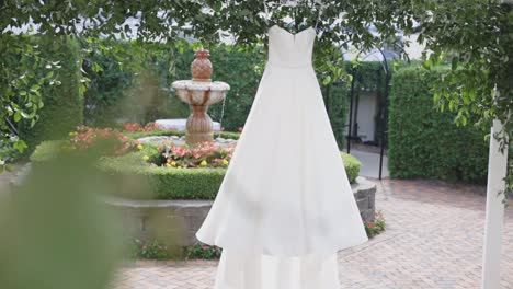 Wedding-dress-hangs-in-front-of-fountain