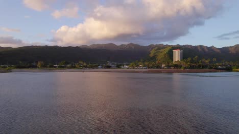 slow-moving-drone-footage-of-East-Honolulu-Hawaii-from-the-water-perspective-with-pink-glow-of-the-setting-sun-reflecting-off-the-water-and-puffy-clouds