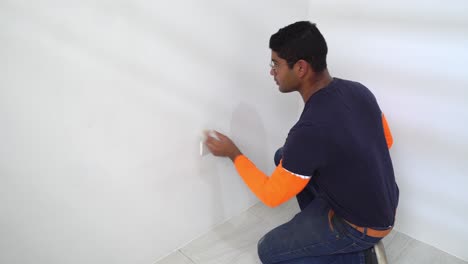 Man-Cleaning-Dry-Painted-Wall-With-Piece-Of-Cloth
