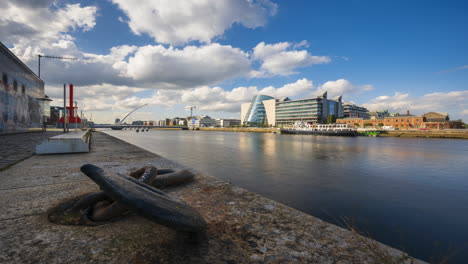 Time-lapse-of-concrete-river-canal-in-Dublin-City-with-large-iron-boat-chain-hook-during-daytime-with-clouds-in-the-sky-reflecting-on-Liffey-river-in-Ireland