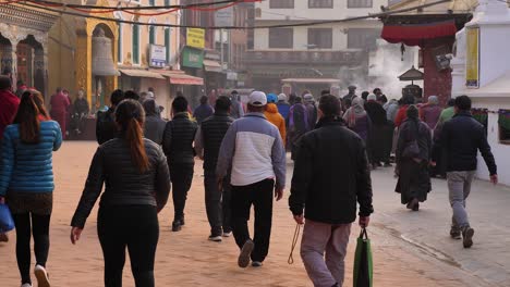 Ground-level-close-shot-of-people-walking-around-the-outer-part-of-Boudhanath-Temple,-Kathmandu,-Nepal