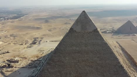 Aerial-of-the-iconic-Great-Pyramids-of-Giza-and-the-sprawling-Pyramids-Plateau-in-Egypt,-epitomizes-the-concept-of-ancient-marvels-and-timeless-cultural-heritage