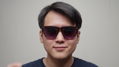 Close-up-view-of-a-Chinese-man-putting-on-his-sunglasses-and-start-smiling