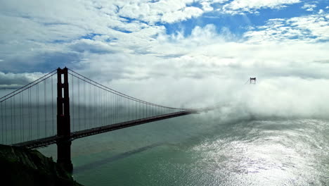 Aerial-drone-shot-above-golden-gate-bridge-in-San-Francisco,-USA-with-white-clouds-passing-by-at-daytime