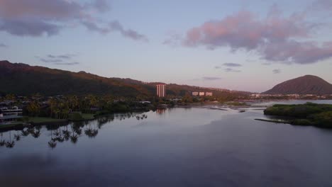 Imágenes-De-Drones-A-Través-De-Aguas-Tranquilas-Y-Bancos-De-Arena-En-El-Este-De-Honolulu-En-La-Isla-De-Oahu-En-Hawaii-Con-El-Brillo-Alpino-De-La-Reciente-Puesta-De-Sol-Reflejando-El-Rosa-En-Las-Nubes-Y-La-Montaña-Púrpura