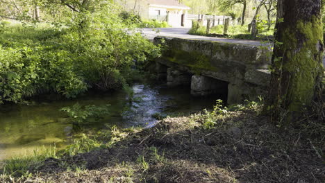 Water-slowly-flows-below-calm-empty-country-road-bridge-in-Galicia-Spain