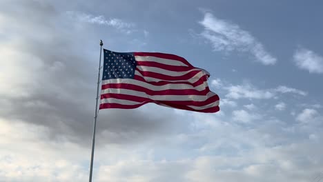Große-Amerikanische-Flagge-Weht-Im-Wind-Vor-Einem-Sonnigen-Blauen-Himmel-Und-Weißen-Wolken-Am-Späten-Nachmittag