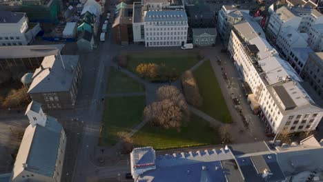 Parque-Austurvöllur-En-El-Centro-De-La-Ciudad-De-Reykjavik-Durante-La-Puesta-De-Sol,-Aéreo