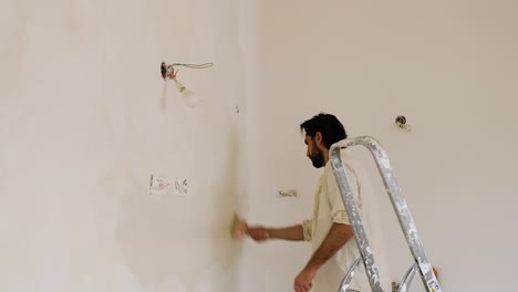 A-Man-Using-Large-Paintbrush-Creating-Brush-Strokes-On-The-Wall-During-Limewash-Painting