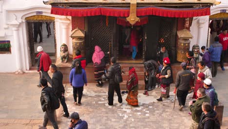 People-walking-past-the-entrance-to-the-central-Stupa,-Boudhanath-Temple,-Kathmandu,-Nepal