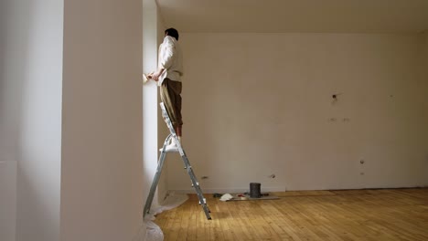 Man-On-Stepladder-Applying-Limewash-Paint-On-House-Wall-With-Strokes-Of-Brush