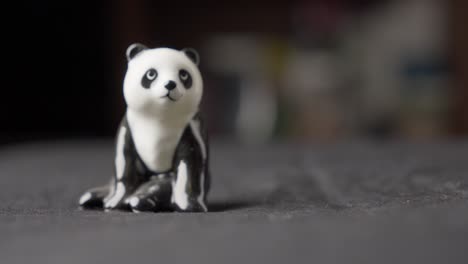 Hand-Picking-Up-Miniature-Figurine-Toy-Panda,-Close-Up-With-Blurred-Background