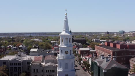 Toma-Panorámica-Aérea-De-Primer-Plano-De-La-Aguja-En-La-Cima-De-La-Iglesia-De-San-Miguel-En-Charleston,-Carolina-Del-Sur