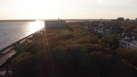 Low-aerial-shot-flying-over-White-Point-Garden-at-Oyster-Point-in-Charleston,-South-Carolina-during-sunset