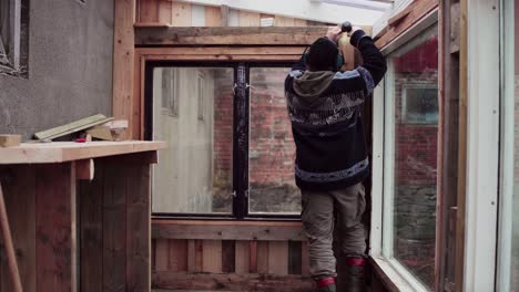 Greenhouse-Construction---Man-Assembling-Wooden-Interior-By-The-Window