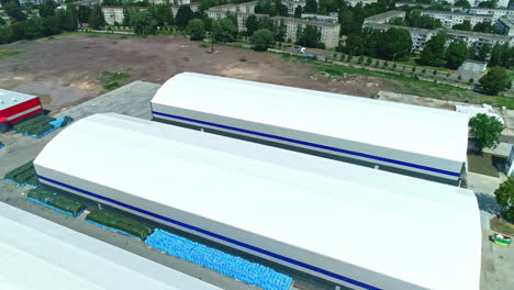 Drone-view-over-two-large-white-storage-facilities-on-the-edge-of-a-residential-area