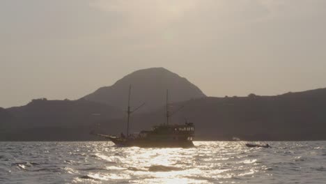 Yacht-cruises-the-waters-near-Komodo-Island,-with-a-backdrop-of-a-small,-mountainous-island