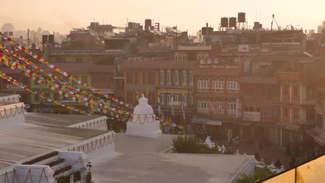 Vistas-Del-Atardecer-De-Banderas-De-Oración-Y-Edificios-Circundantes-En-El-Templo-Boudhanath,-Katmandú,-Nepal