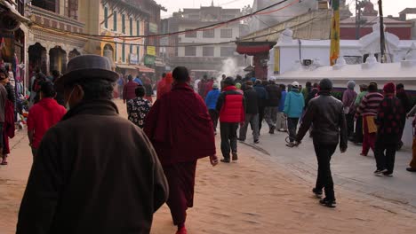 Ground-level-shot-of-people-walking-around-the-outer-part-of-Boudhanath-Temple,-Kathmandu,-Nepal