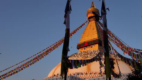 Wide-low-shot-of-pigeons-flying-around-the-central-Stupa-of-Boudhanath-Temple-at-sunset,-Kathmandu,-Nepal