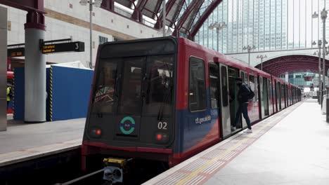 DLR-Zug-Wartet-Am-Bahnsteig-Mit-Einsteigenden-Passagieren-Am-Bahnhof-Canary-Wharf